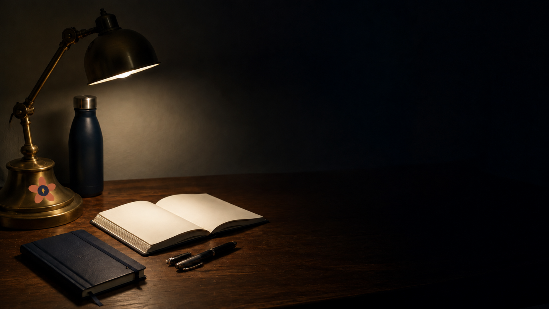 A notebook and pen under a warm desk lamp